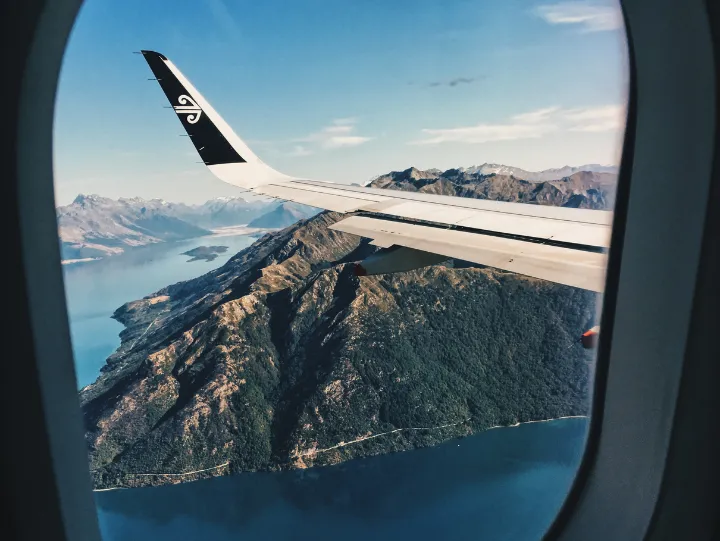 Air New Zealand aircraft flying over the stunning landscapes of Queenstown, showcasing the region's natural beaut